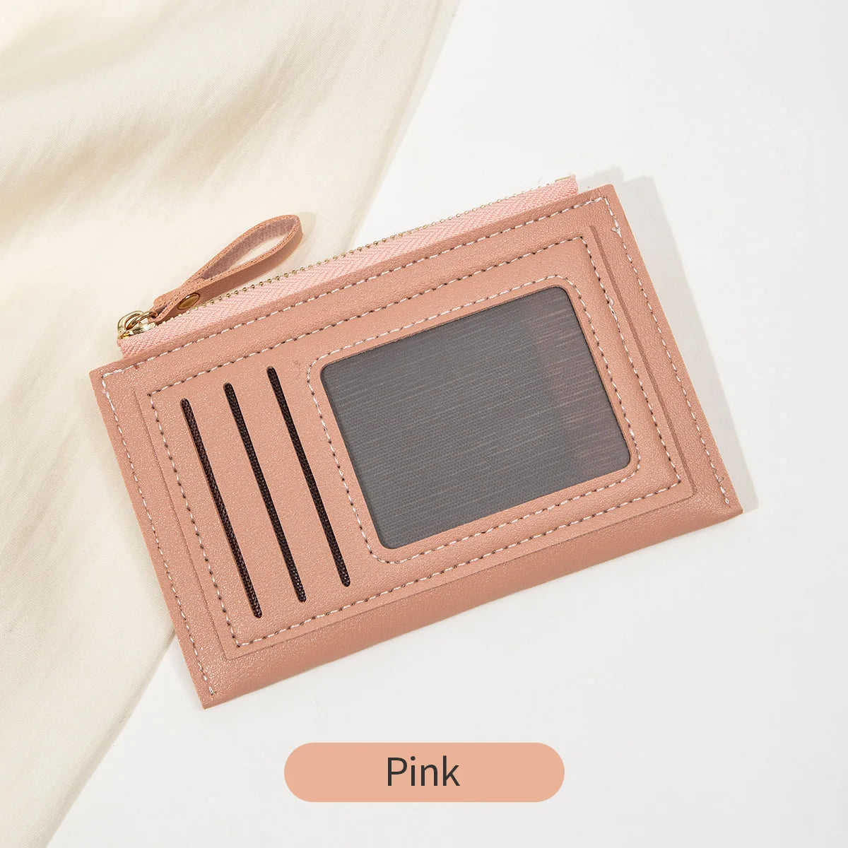 Portefeuille en cuir PU rose minimaliste avec fenêtre transparente et sangle en cuir sur fond blanc.