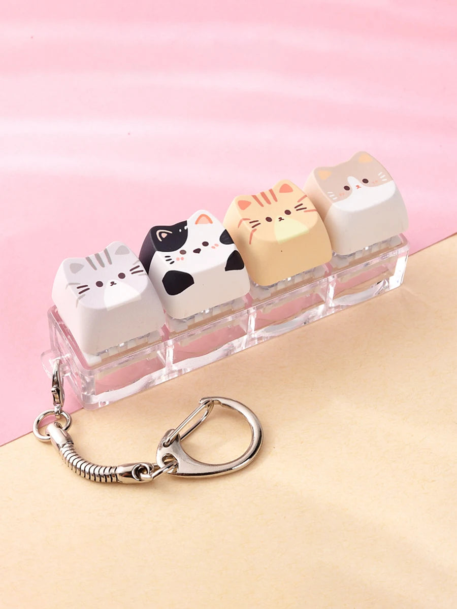 A row of pink and cream cat-themed keycaps or fidget toys displayed on a clear plastic tray with a silver bag charm.