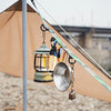 A durable outdoor camping crossbody strap with a lantern and a metal bell hanging from it.