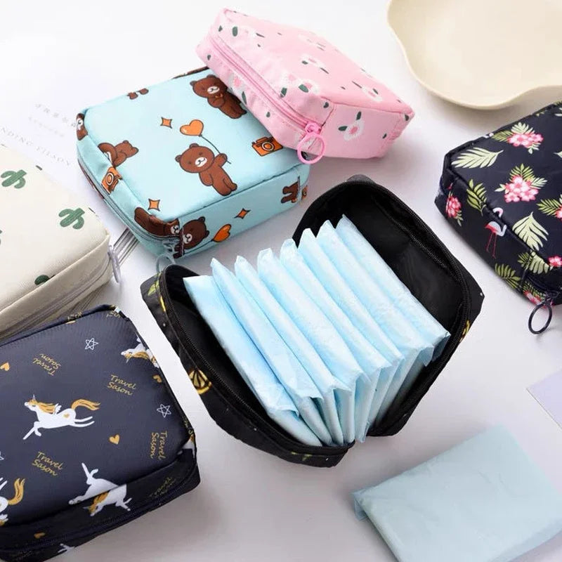 Various pink and blue fabric pouches and a black storage case filled with light blue sanitary pads.