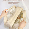 A beige large opening design pouch filled with skincare products and cosmetics being held by a hand.