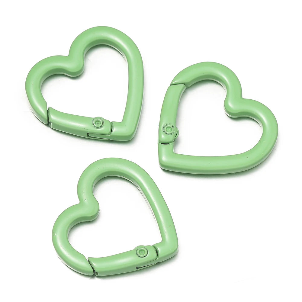 Three heart-shaped metal spring clasps in light green color shown against a white background.