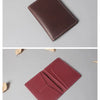 A dark burgundy genuine cowhide leather passport and ticket holder displayed at an angle.