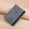 A gray leather passport holder with a black trim and a stylized airplane icon is shown on a light background.