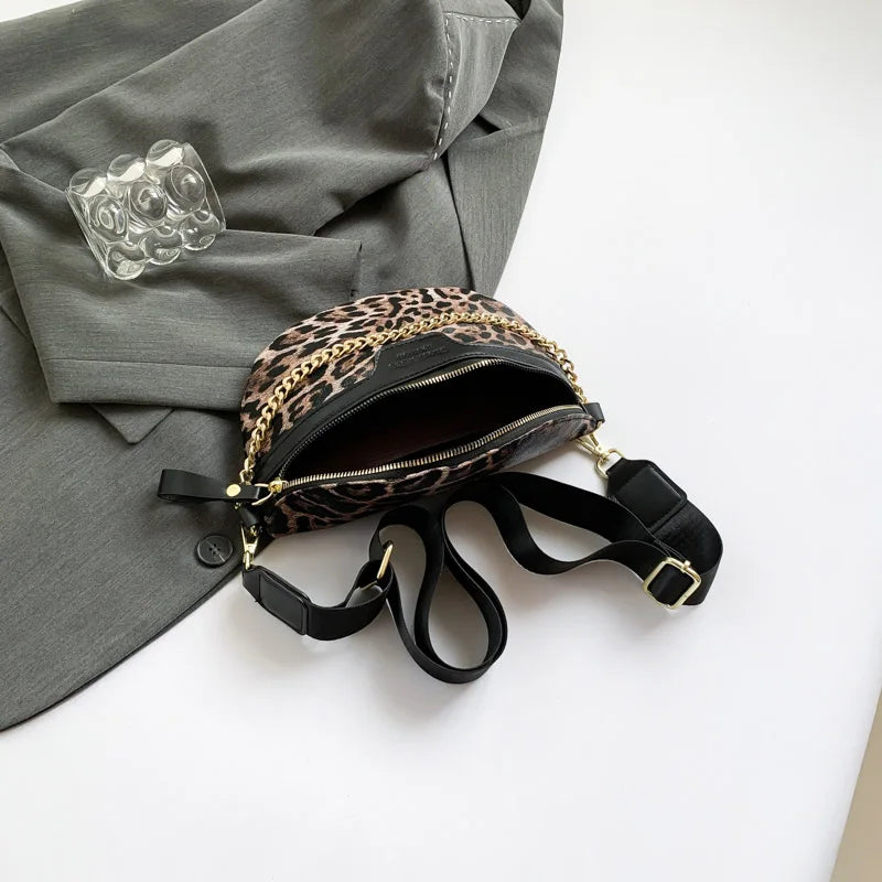 Leopardenmuster-Crossbody-Tauschtasche mit goldfarbenem Kettenriemen, liegt auf einem grauen Blazer.