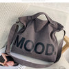 A dark gray canvas tote bag featuring the word MOOD printed in large black letters, resting on a light surface.