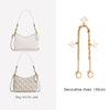 A light pink leather crossbody bag with a gold decorative chain and charm.
