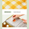 A close-up of a textured yellow and white checkered cloth and a thickened aluminum foil lining for an insulated picnic tote.