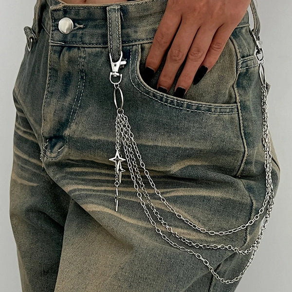 A close-up of a denim pant pocket featuring a silver punk star chain belt with pearl accents hanging from the button.
