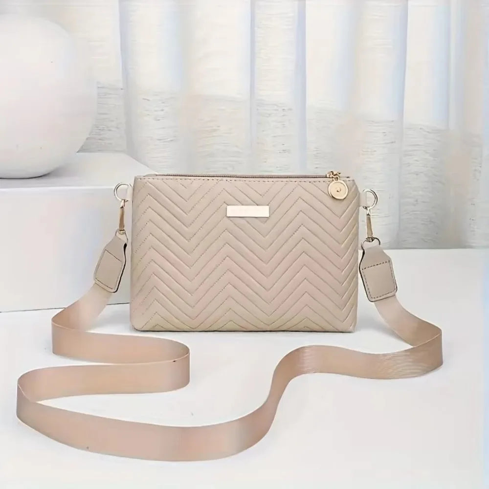 A beige quilted leather crossbody bag with a gold chain strap resting on a white surface.