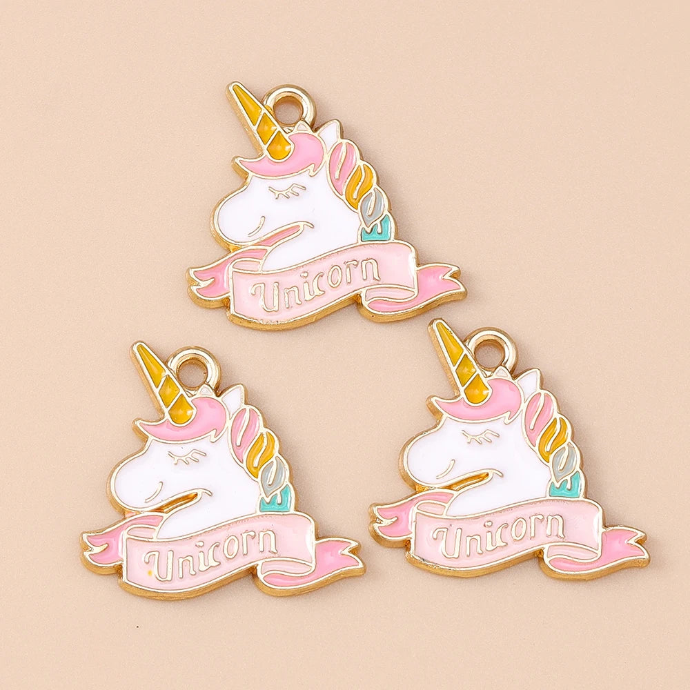 Two gold-toned unicorn horse charm pendants with pink and iridescent accents on a beige background.
