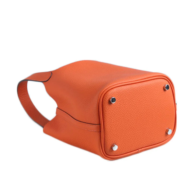 Orangefarbener, echter Leder-Bucket-Bag mit Riemen und silberner Hardware.