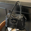 Bolso cruz de cuero suave negro de lujo con herrajes plateados, mostrado sobre una superficie oscura.