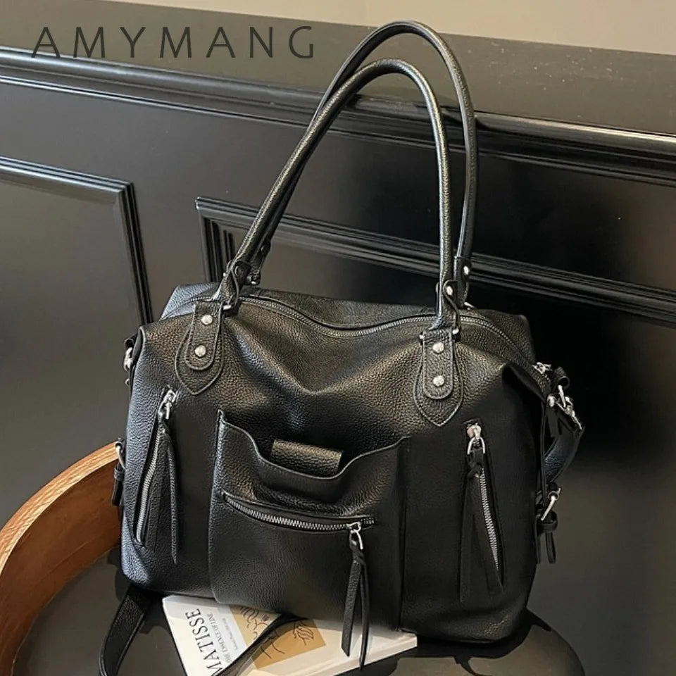 Bolso cruz de cuero suave negro de lujo con herrajes plateados, mostrado sobre una superficie oscura.