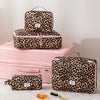 A leopard print large capacity waterproof travel makeup organizer bag in pink and black resting on a pink box.