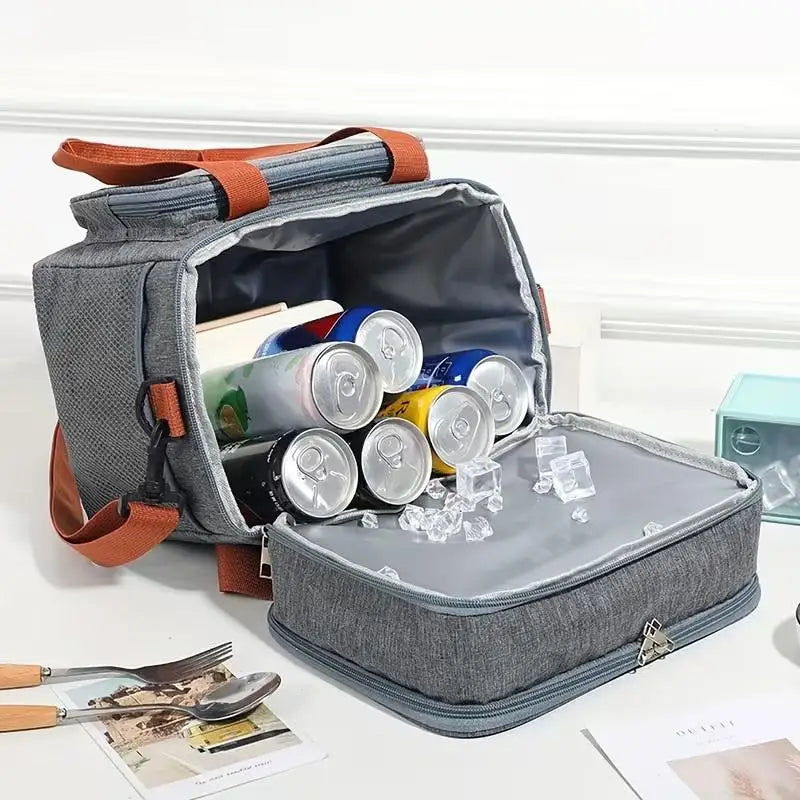 A gray insulated double-layer lunch bag is open, showing compartments filled with various food items and ice.