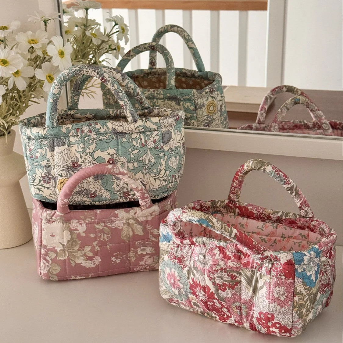 A pink quilted fabric storage basket with floral patterns is displayed on a white surface.
