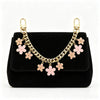 Schwarze Crossbody-Tasche mit goldfarbenem Kettenriemen, verziert mit rosa Perlenblüten.