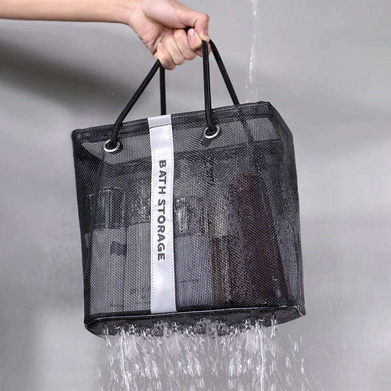 A black mesh drainage shower tote with handles is being filled with water.