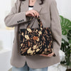 A woman holds a brown blazer and a black leopard print cloth tote bag.