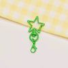 A green star-shaped metal keychain clasp set resting on a yellow checkered cloth.
