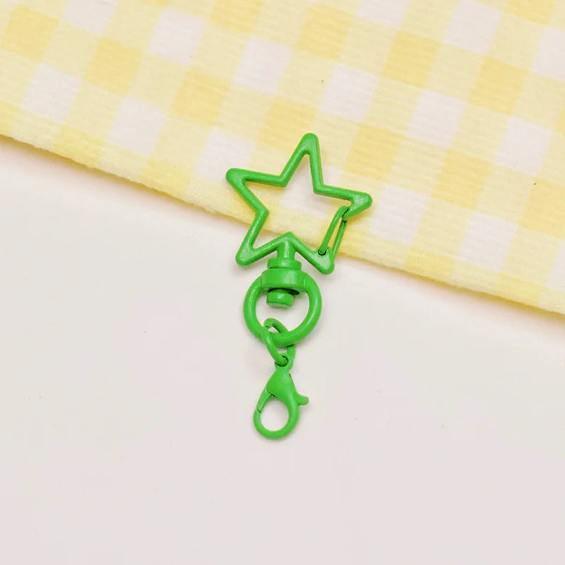 A green star-shaped metal keychain clasp set resting on a yellow checkered cloth.