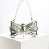 Silver acrylic bow clasp mini handbag with a clear crystal chain strap displayed on a white pedestal.
