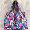 A floral patterned shopping tote bag featuring pink, white, and blue flowers.