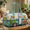 A light blue quilted travel duffel bag with a green trim and decorative window details resting on a wooden surface.