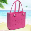 A bright pink portable EVA beach tote bag with perforated sides is shown on a sandy beach with blue ocean in the background.