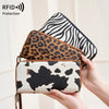 A hand holds a leopard print RFID-blocking tri-fold wallet with a black and white zebra print cover.