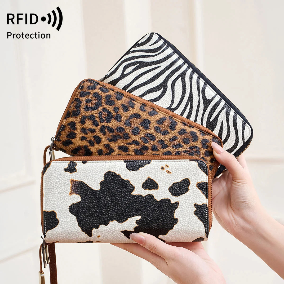 A hand holds a leopard print RFID-blocking tri-fold wallet with a black and white zebra print cover.