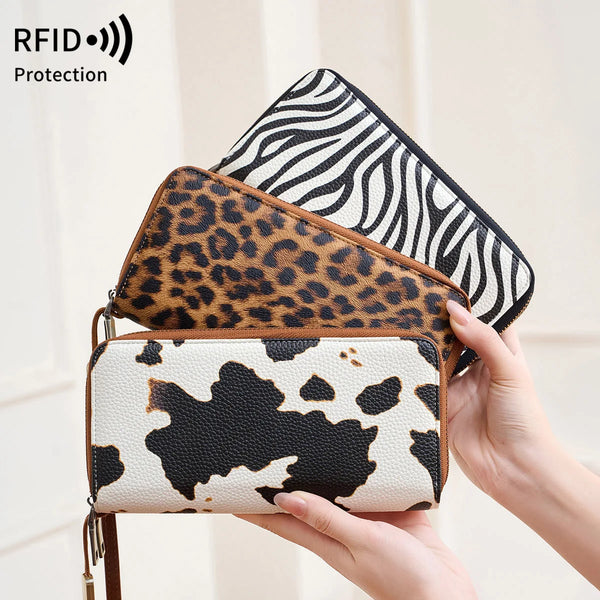 A hand holds a leopard print RFID-blocking tri-fold wallet with a black and white zebra print cover.