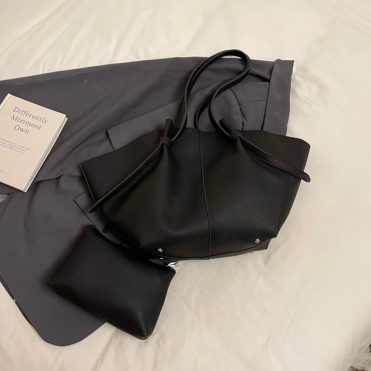 A black luxury PU leather shoulder tote bag resting on a gray fabric background.