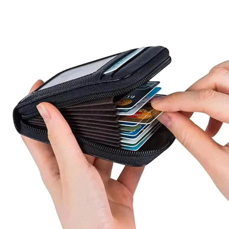 A hand holds an open black slim RFID blocking leather wallet displaying several credit cards.
