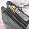 A close-up of a black leather zipper wallet with gold hardware and a textured silver accent.