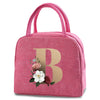 A pink insulated canvas lunch bag with a gold letter B print and pink fabric handles.