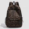 A brown leopard print laptop backpack featuring padded straps and a logo patch.