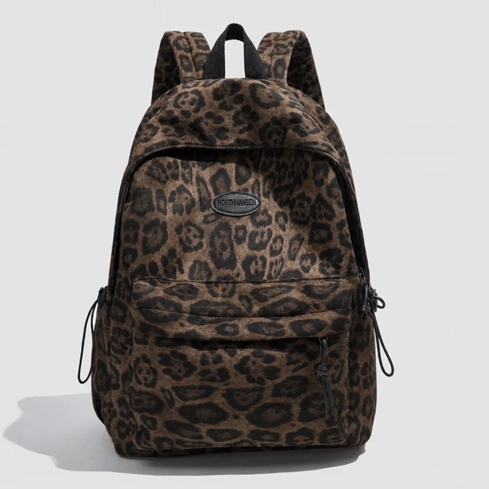 A brown leopard print laptop backpack featuring padded straps and a logo patch.