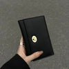 A hand holds a black compact women's card holder wallet with a gold cloud emblem.