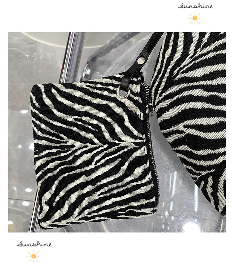 Schwarz-weißes Zebra-Print-Canvas-Crossbody-Taschen, präsentiert auf einer Glasoberfläche.