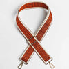 A brown and cream patterned adjustable crossbody bag strap with a gold buckle.