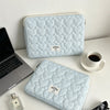 Light blue quilted laptop sleeve with a heart pattern resting on a white desk.