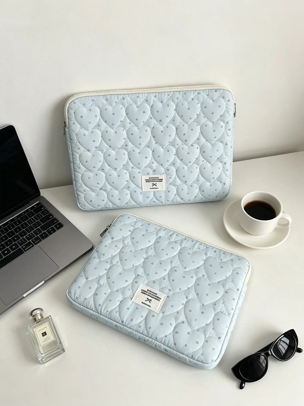 Light blue quilted laptop sleeve with a heart pattern resting on a white desk.