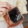A hand holds a brown leather coin purse with a gold chain and a dark lining, featuring a metallic flap.