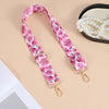 Pink floral patterned nylon crossbody bag strap with a gold-toned metal buckle