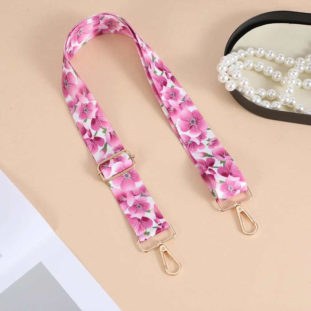 Pink floral patterned nylon crossbody bag strap with a gold-toned metal buckle