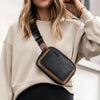 A woman wearing a beige sweater holds a black and brown PU leather crossbody waist bag.