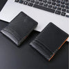 Black textured credit card holder wallet placed on a dark surface next to a laptop keyboard