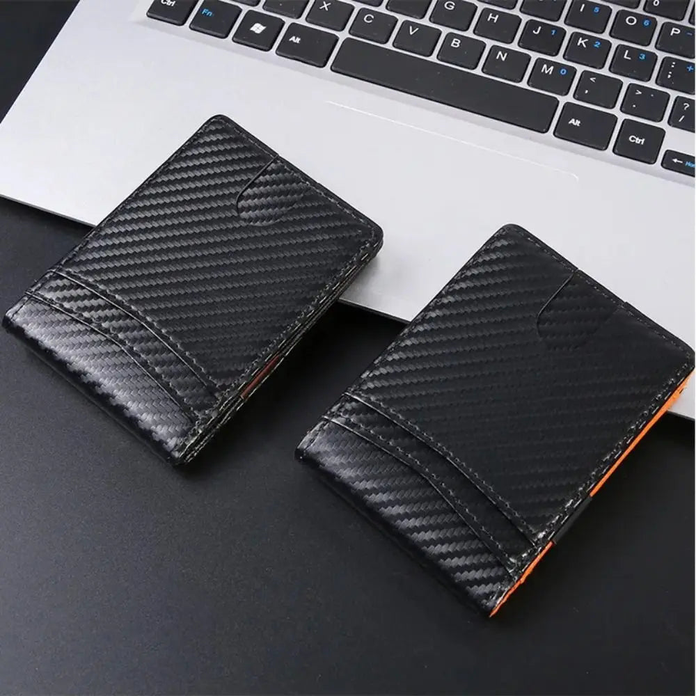 Black textured credit card holder wallet placed on a dark surface next to a laptop keyboard